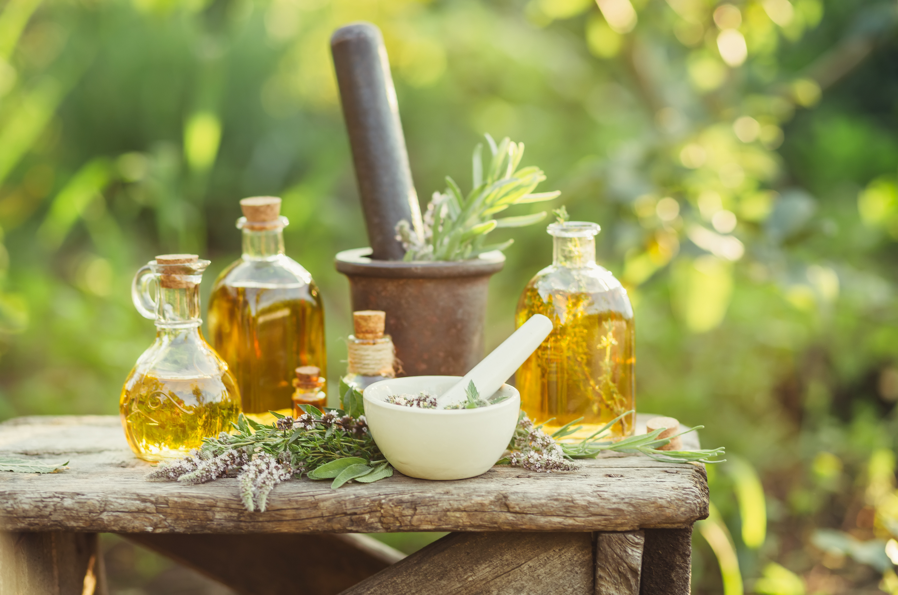 Various massage and cosmetic oils in glass bottles wooden on the table in the garden